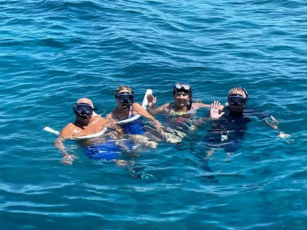 Four snorkelers waving from the water over the Key West reef